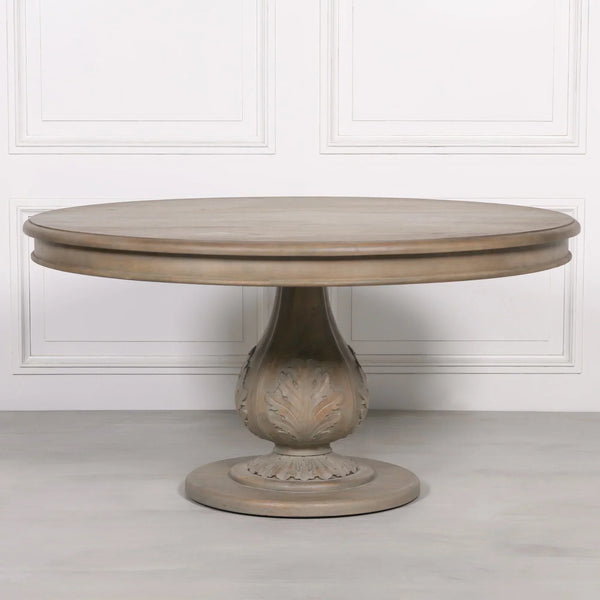 Round wooden dining table with carved pedestal base and light oak finish