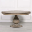 Round wooden dining table with carved pedestal base and light oak finish