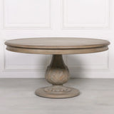 Round wooden dining table with carved pedestal base and light oak finish