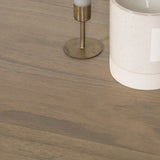 Close view of wood coffee table surface with brass candle holder and ceramic cup