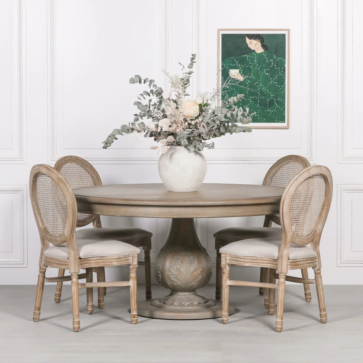 Round wooden dining table with carved pedestal base and four rattan back chairs