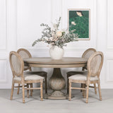 Round wooden dining table with carved pedestal base and four rattan back chairs