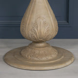 Carved wood table base with leaf detailing and circular foot on light grey floor