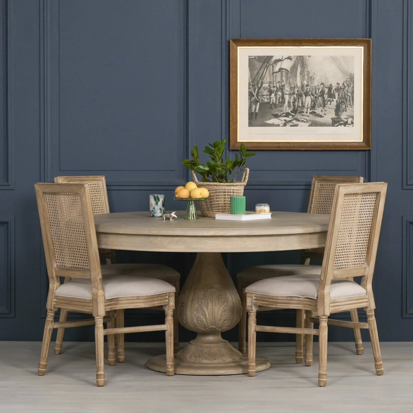 Round wood pedestal dining table with four rattan back chairs in classic room setting