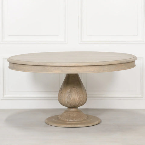 Round oak dining table with carved pedestal base against a white panelled wall