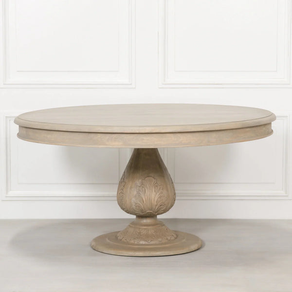 Round oak dining table with carved pedestal base against a white panelled wall