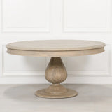 Round oak dining table with carved pedestal base against a white panelled wall