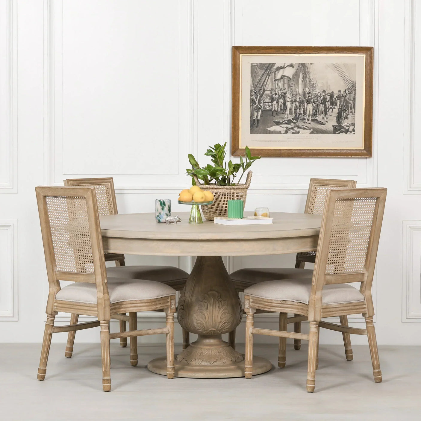 Round wooden dining table with four cane-back chairs in light wood finish