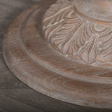 Rustic wooden dining table base with carved leaf detail on dark wood flooring