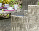 Close-up of rattan outdoor dining set with glass table and matching woven chairs