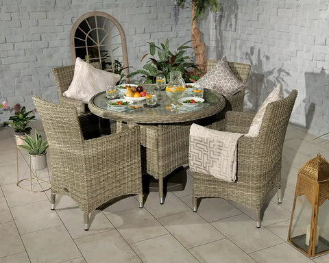 Rattan garden dining set with glass round table and four armchairs on tiled patio