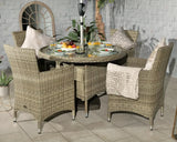 Rattan outdoor dining set with glass-top table, four armchairs, and neutral cushions