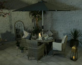 Rattan garden dining set with four chairs, round table, and parasol on tiled patio at night