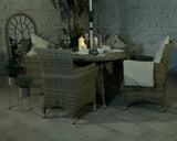 Rattan garden dining set with four armchairs, round table, candles and glassware on patio