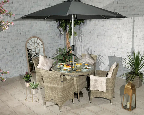 Rattan garden dining set with four cushioned chairs, glass table, and large grey parasol