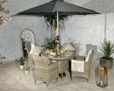 Rattan garden dining set with four cushioned chairs, glass table, and large grey parasol