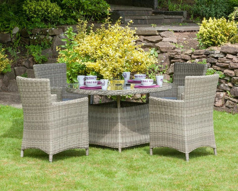 Grey rattan garden dining set with four armchairs and glass-top table on grass