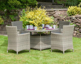 Grey rattan garden dining set with four armchairs and glass-top table on grass