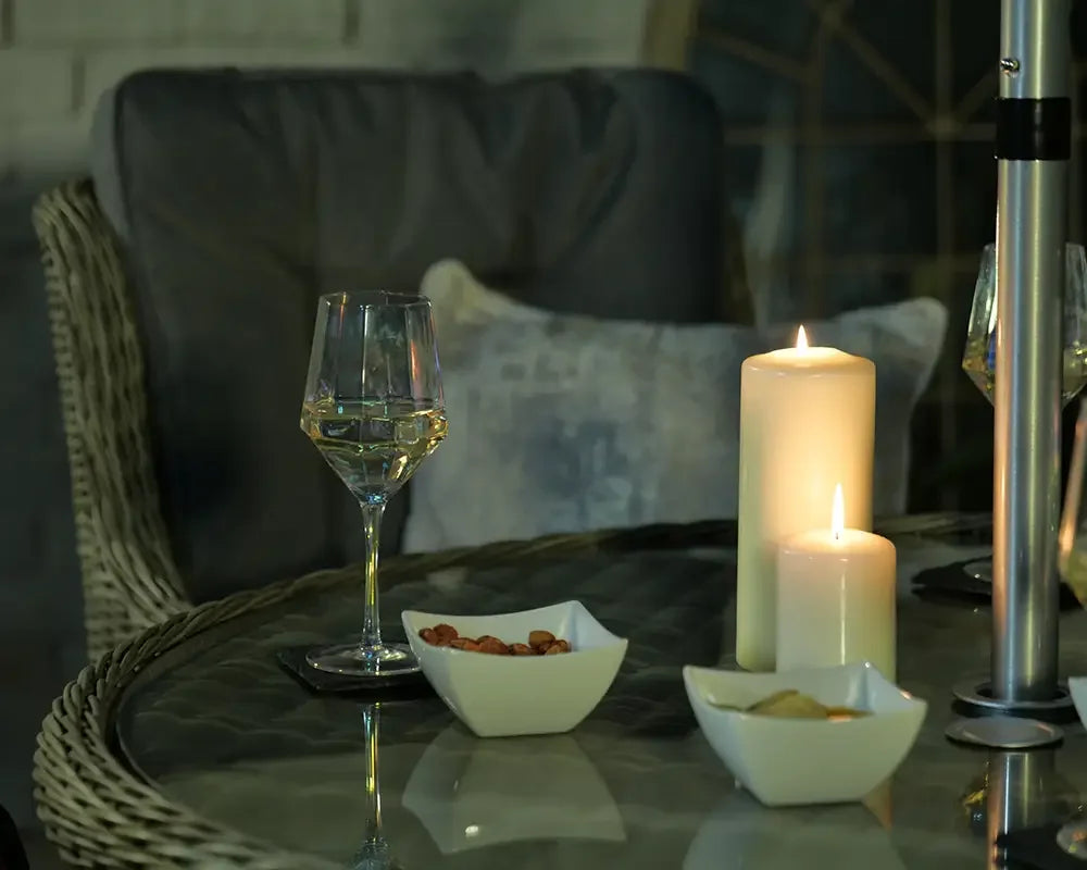 Rattan dining set with glass tabletop, wine glass, candles, and snack bowls