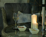 Rattan dining set with glass tabletop, wine glass, candles, and snack bowls