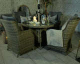 Rattan dining set with four cushioned chairs and round glass table arranged indoors