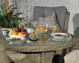 Rattan dining set with glass table, grey cushioned chair, plated fruit and salad, outdoor setting