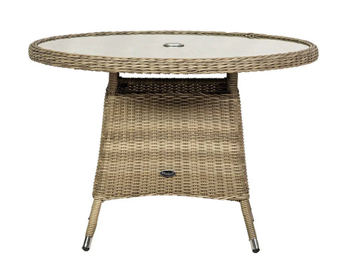 Round rattan outdoor dining table with glass top and umbrella hole, neutral tone finish