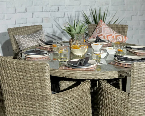 Round rattan dining set with glass top, place settings, and scatter cushions