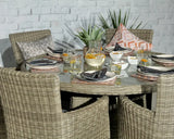 Round rattan dining set with glass top, place settings, and scatter cushions