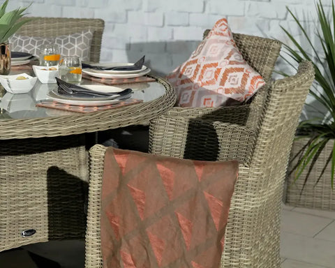 Rattan garden dining set with glass table and cushioned chairs, set for outdoor meal