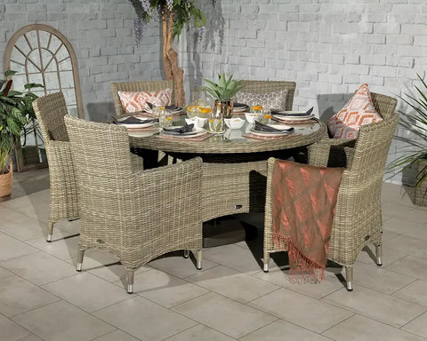 Round rattan dining set with glass top and four armchairs set for a meal indoors