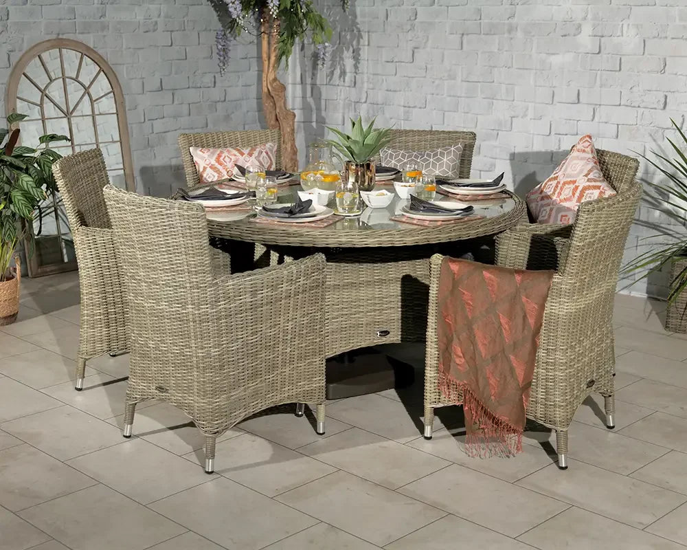 Round rattan dining set with glass top and four armchairs set for a meal indoors
