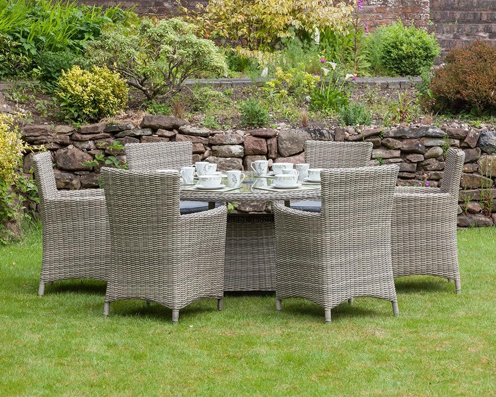 Grey rattan garden dining set with six chairs and glass top table on lawn