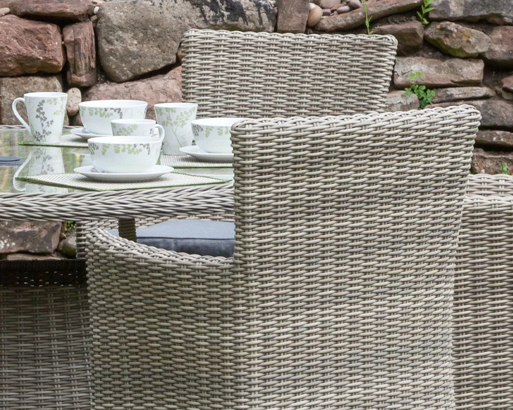 Close view of rattan outdoor dining set with cushioned chairs and glass table top