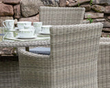 Close view of rattan outdoor dining set with cushioned chairs and glass table top