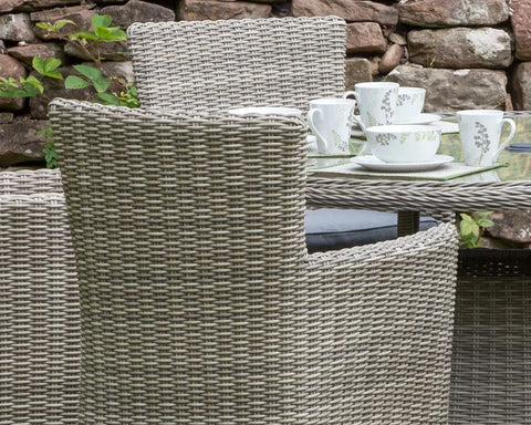 Close-up of rattan dining chair and glass table set with cups outdoors