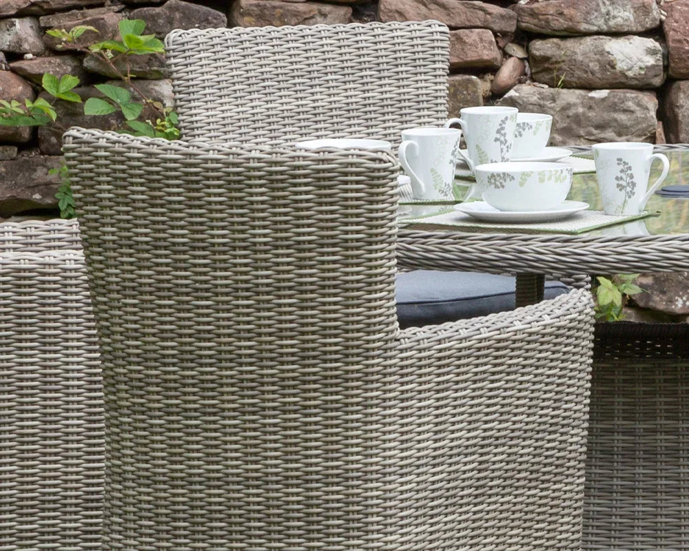 Close-up of rattan dining chair and glass table set with cups outdoors