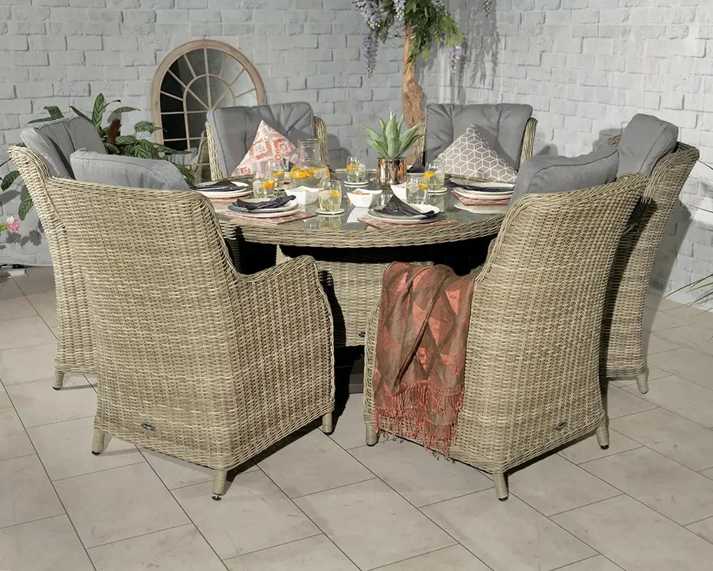 Round rattan dining set with six cushioned chairs and table set for dinner on tiled patio