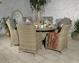 Rattan garden dining set with six cushioned chairs and round table, plants in background