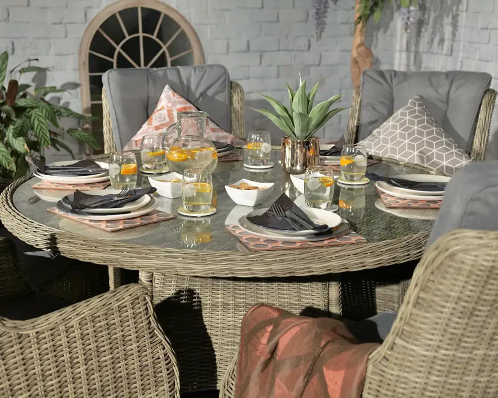 Rattan garden dining set with grey cushions and glass tabletop, set for outdoor meal