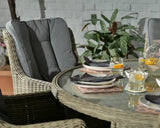 Rattan garden dining set with grey cushioned chairs and round glass table set for four