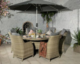 Rattan outdoor dining set with round table, six cushioned chairs and grey parasol on patio