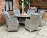 Grey rattan outdoor dining set with round glass table and six cushioned chairs on patio