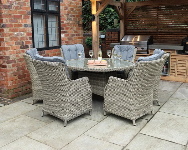 Grey rattan garden dining set with six cushioned chairs and glass top table on patio