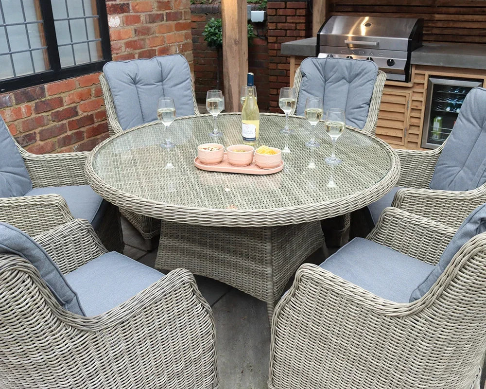 Rattan dining set with six cushioned chairs and round glass table in an outdoor patio area
