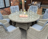 Rattan dining set with six cushioned chairs and round glass table in an outdoor patio area