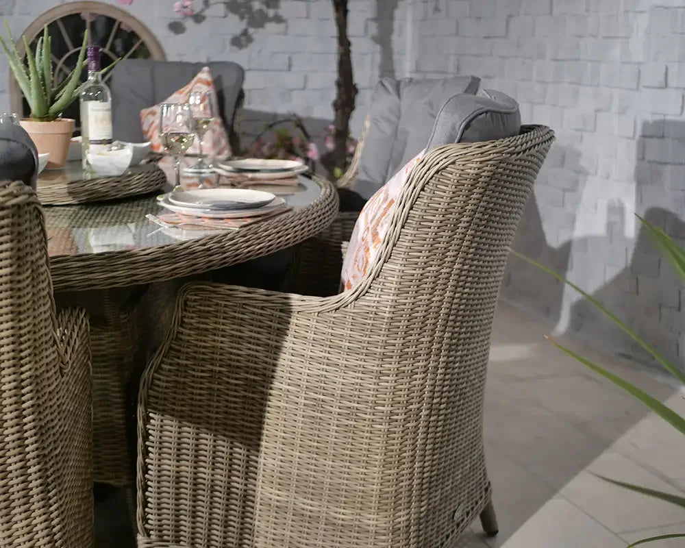 Rattan outdoor dining set with glass-top table and cushioned chairs on tiled patio