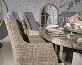 Rattan dining table with glass top and cushioned wicker chairs set for dinner