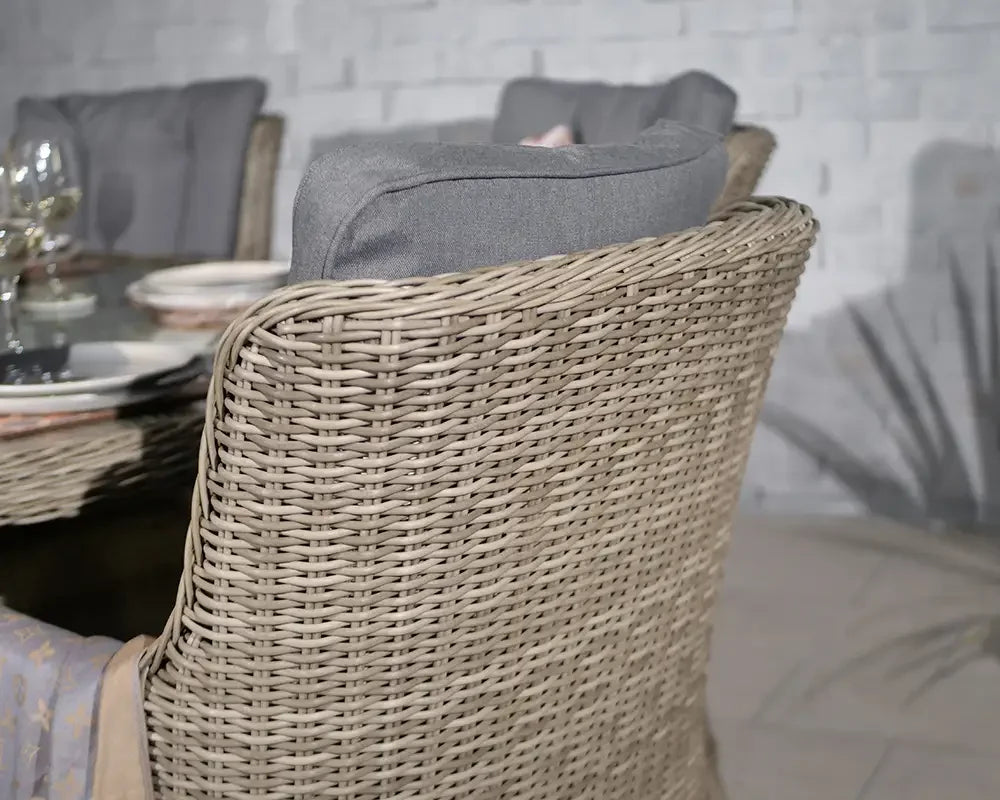 Rattan dining chair with grey cushion beside glass table set with plates and glassware