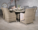 Round rattan dining set with six cushioned chairs and a table set for dinner indoors